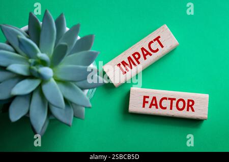 Symbol für Aufprallfaktor. Holzblöcke mit den Worten Impact Factor. Schöner grüner Hintergrund mit saftiger Pflanze. Business and Impact Factor Konzept. Cop Stockfoto