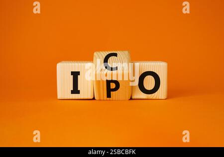 ICO vs. IPO-Symbol. Gedrehte Holzwürfel mit den Worten IPO und ICO. Wunderschöner orangefarbener Hintergrund. ICO vs IPO und Geschäftskonzept. Kopierbereich Stockfoto