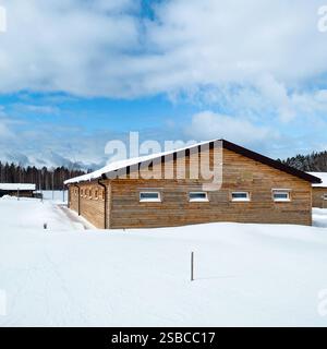 Bauernhof in der Winterlandschaft. Holzscheune mit kleinen verschneiten Witwen. Stockfoto