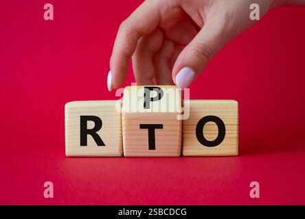 RPO vs. RTO-Symbol. Geschäftsmann-Hand dreht Holzwürfel und ändert das Wort RTO in RPO. Schöner roter Hintergrund. Geschäftskonzept. Kopierbereich Stockfoto