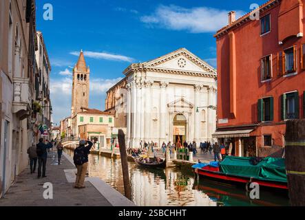 Tourismus in Venedig. Blick auf den Rio San Barnaba Kanal mit Gondeln, alter Kirche und Touristen im historischen Viertel Dorsoduro Stockfoto