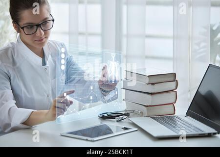 Weibliche Ärztin verwendet moderne Technologien, virtuellen Bildschirm mit Hologramm. Das Konzept der Medizin der Zukunft. Stockfoto