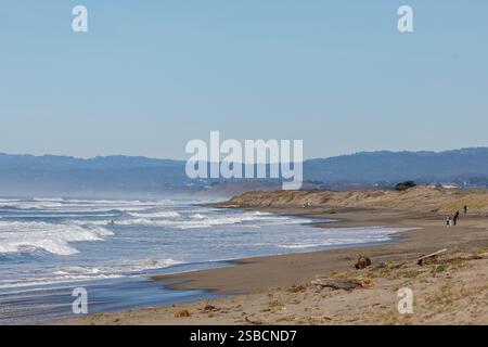 Eine kleine Gruppe von Menschen beobachtet, wie Wind und Meereswellen am abgelegenen Sandstrand abstürzen, nachdem der Wintersturm aufgelöst ist Stockfoto