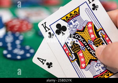 Eine Nahaufnahme eines Pokerspielers mit einem Ass und einem König von Clubs, auch bekannt als „Ace-King“ oder „Big Slick“. Der grüne Filztisch, Pokerchips Stockfoto