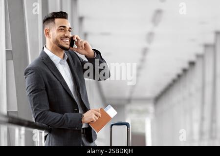 Mobile Anrufe. Lächelnder Junger Geschäftsmann Aus Dem Nahen Osten Im Gespräch Am Handy Am Flughafen Stockfoto