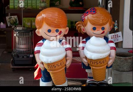 Puppen für Jungen und Mädchen, die Nissei-Eiskegel halten, sind beliebte Werbeanzeigen in Geschäften, die Eis verkaufen in Japan. Stockfoto