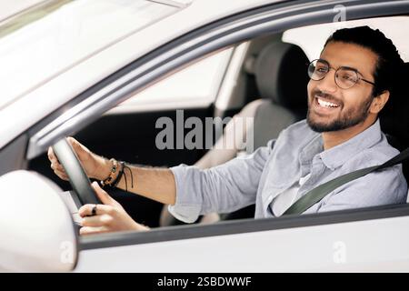 Happy Millennial Middle-Eastern guy driving Auto, Seitenansicht Stockfoto