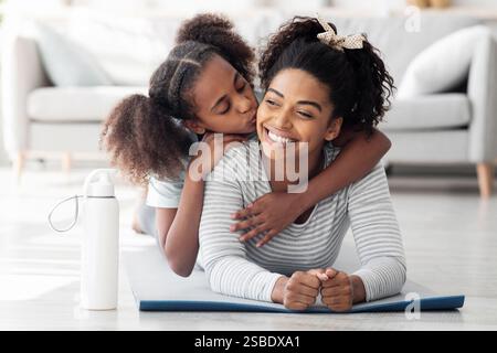 Glückliche schwarze Mutter und Tochter kuscheln beim Yoga üben Stockfoto