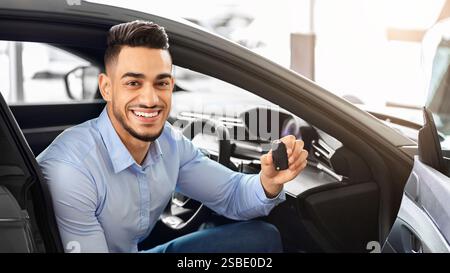 Hübscher arabischer Mann, der im Auto sitzt und den Schlüssel hält Stockfoto