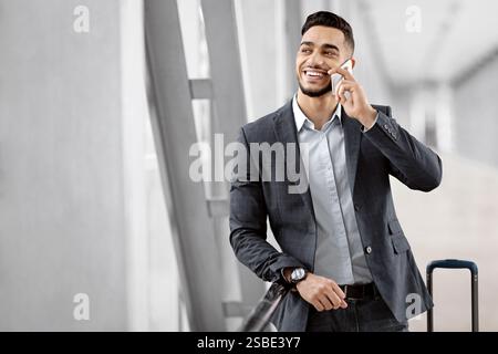 Hübscher Junger Arabischer Geschäftsmann, Der Auf Dem Handy Spricht, Während Er Im Flughafenterminal Wartete Stockfoto