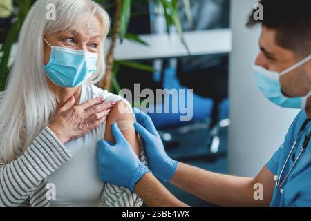 Reife Frau wird gegen Grippe geimpft, Arzt wendet Pflaster an Stockfoto