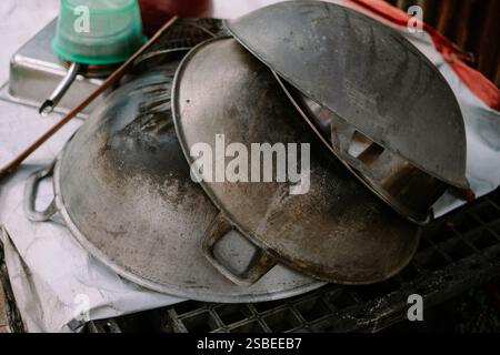 Stapel gut gebrauchter Woks mit Anzeichen von Kochen und Verschleiß. Stockfoto
