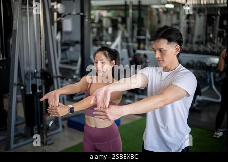 Sportliche asiatische Männer und Frauen in Sportbekleidung dehnen ihre Muskeln zusammen, bevor sie ihr Training im Fitnessstudio beginnen. Gesunder Lebensstil, Hobby Stockfoto