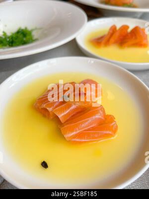 Sashimi in Mangosaft auf Teller. Lachsscheiben. Fisch und Meeresfrüchte und asiatische Küche. Gesunde Lebensmittel und Langlebigkeit. Stockfoto