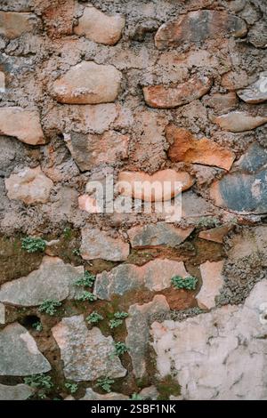 Nahaufnahme einer strukturierten Steinmauer mit Moos. Stockfoto