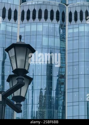Nahaufnahme eines traditionellen Laternenpfahls in Hongkong, der einen modernen Glashochhaus reflektiert. Die Glasfassade zeigt eine verzerrte Reflexion des c Stockfoto