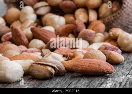 Gemischte Nüsse, getrocknete Früchte auf rustikalem Tisch, verschiedene Art von gesundem Essen Stockfoto