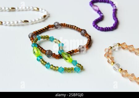 Armbänder mit Perlen und braunen, grünen und violetten Perlen. Stilvolle trendige Modeaccessoires, Modeschmuck, handgefertigte Bijouterie auf weißem Hintergrund. Stockfoto