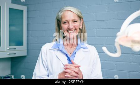 Lächelnde Zahnärztin in einer Zahnarztpraxis mit professionellem weißen Mantel Stockfoto