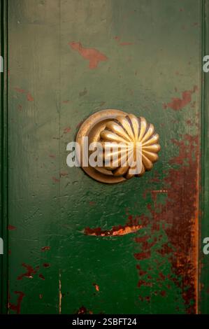 Verwitterte grüne Holztür mit kunstvollem Messingknopf Stockfoto