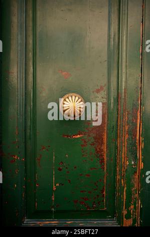 Verwitterte grüne Holztür mit kunstvollem Messingknopf Stockfoto