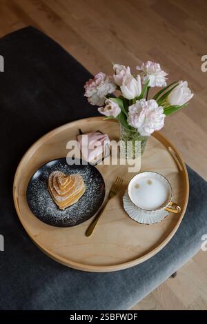 Stapel herzförmiger Pfannkuchen mit Kaffee, Blumen und Geschenk auf einem Tablett Stockfoto