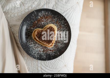 Herzförmige Pfannkuchen auf Platte auf neutralem Hintergrund Stockfoto
