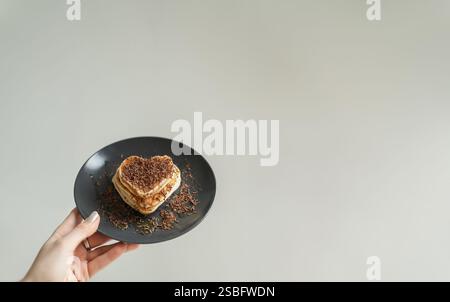 Handplatte mit herzförmigen Pfannkuchen gegen weißen Backboden Stockfoto