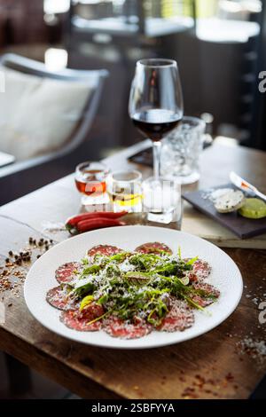 Rindfleisch-Carpaccio. Borettane-Zwiebeln, sonnengetrocknete Tomaten, Trüffeldressing, Rucola-Salat, Parmesankäse. Traditionelle italienische Antipasti-Snacks serviert Stockfoto