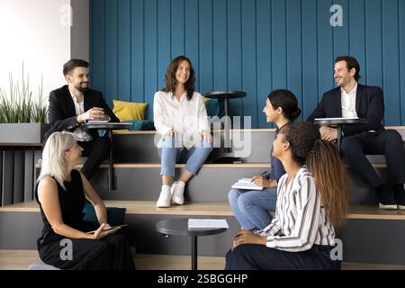 Glückliche Teamkollegen, die während der Pause, des Briefings oder des Seminars scherzen und lachen Stockfoto