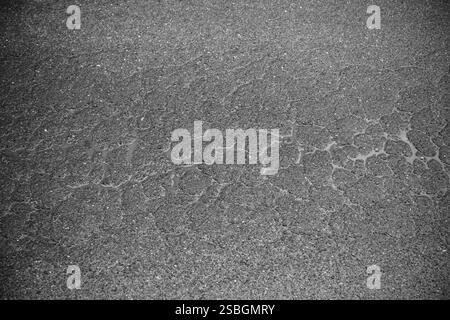 Nahaufnahme einer gerissenen und verwitterten Oberfläche, möglicherweise Asphalt oder ähnliches Material. Zeigt Anzeichen von Alter und Verschlechterung. Stockfoto