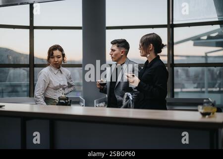 Drei Geschäftsleute führen während einer Kaffeepause in einem modernen Büro Gespräche. Stockfoto