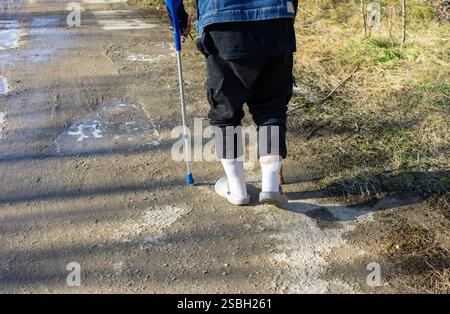 Alter Mann mit Gehhilfe im Winter auf schwarzem Eis, Rutschgefahr Stockfoto