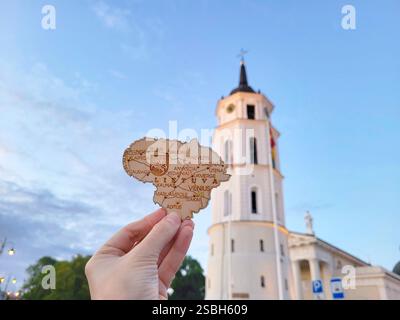 Vilnius, Litauen - 14. 07. 2022 - Souvenir - Holzkarte von Litauen in den Händen eines Mannes vor dem Uhrturm auf dem Domplatz im Cent Stockfoto