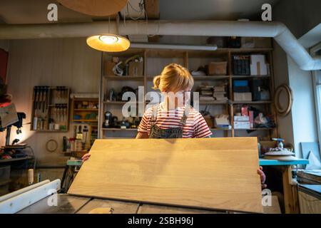 Ernsthafte Schreinerin prüft Qualität und Zustand der Holzarbeitsfläche in der Handwerkstatt Stockfoto