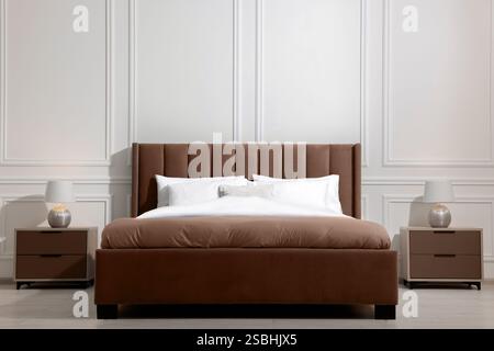 Großes Bett in Mokkahaumschatten und Nachttische drinnen. Trendige Farbe 2025 Jahre im Innendesign Stockfoto