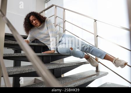 Verletzte Frau auf Treppen im Gebäude nach dem Sturz. Gefährlicher Unfall Stockfoto