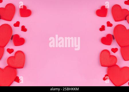 Rosafarbener Valentinstag-Hintergrund mit roten Herzen, verschiedene rote Herzen Layout einfaches Muster auf pastellrosa Hintergrund, Kopierraum von oben. Valentinstag Stockfoto