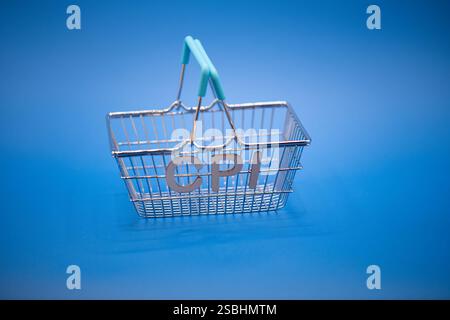 Ein Miniatur-Warenkorb aus Metall vor einem leuchtend blauen Hintergrund, mit Verbraucherpreisindex, Konsumverhalten, Einkaufskosten Stockfoto