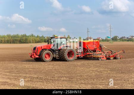 Ein Traktor mit einer pneumatischen Sämaschine säen Samen aus, während er Dünger auf den Boden ausbringt. Ein Bauer säumt seine Paddocks im Frühling mit einem Pn Stockfoto