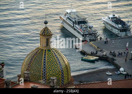 Majolika-gekachelte Kuppel der Kirche Santa Maria Assunta und Passagierfähren in Positano, Amalfiküste, Italien. Stockfoto