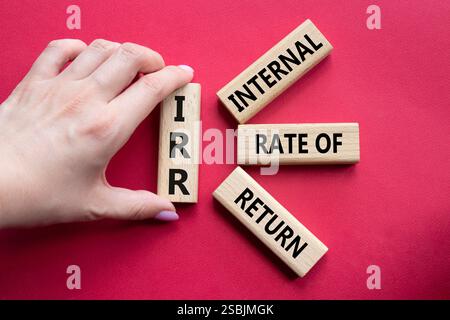 IRR - Internal Rate of Return symbol. Concept word IRR on wooden cubes. Businessman hand. Beautiful red background. Business and IRR concept. Copy spa Stockfoto