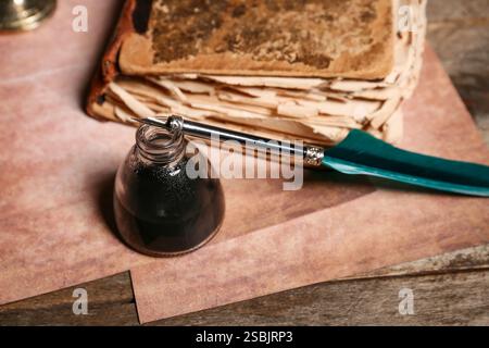 Altes Buch mit Federstift und Tintenfass auf hölzernem Hintergrund Stockfoto