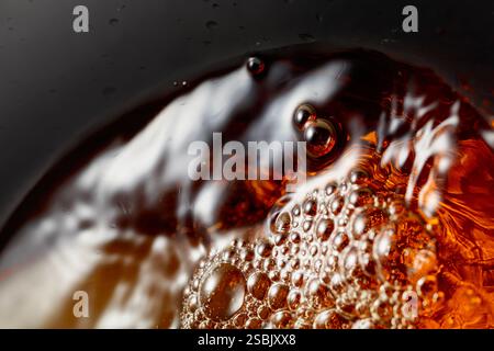 Goldenes Getränk wird in das Glas gegossen und erzeugt wunderschöne Wellen und Spritzer. Selektiver Fokus. Makroaufnahme. Stockfoto