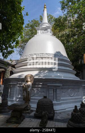 Buddha-Statue vor der weißen Pagode des Gangaramaya-Tempels in Colombo, Sri Lanka Stockfoto