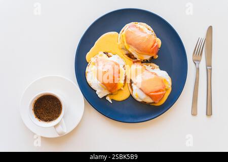 Toast mit Lachs, pochiertem Ei, Frischkäse und Golandsauce und einer Tasse Kaffee. Bruschetta mit pochiertem Ei und Lachs. Offenes Sandwich und eine Tasse Kaffee Stockfoto