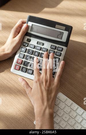 Nahaufnahme der Hände einer Frau mit einem Taschenrechner, perfekt für Themen wie Finanzen, Bildung, Unternehmen, Produktivität und Technologie. Ideal für Stockfoto