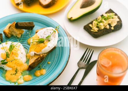 Roggenbrot mit Avocado und pochierten Eiern auf einer blauen Platte auf hellem Hintergrund. Ausgewählter Fokus. Keto Diät, gesundes diätetisches Frühstück. Hohe Qualität Stockfoto
