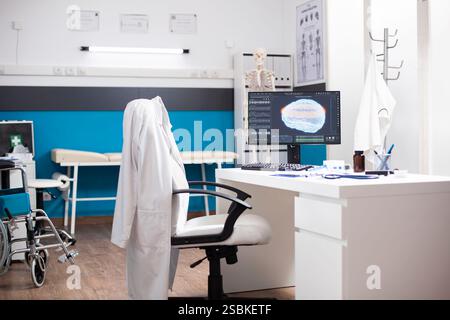 Moderne Klinik-Workstation verfügt über einen Desktop-pc, der Gehirnscans anzeigt, und einen organisierten Schreibtisch im sauberen, leeren Büro. Computermonitor im Krankenhauszimmer zeigt diagnostische Ergebnisse für neurologische Tests. Stockfoto