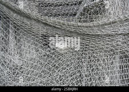 Gehängte graue Fischernetze aus dünnen geknoteten Seilen Stockfoto